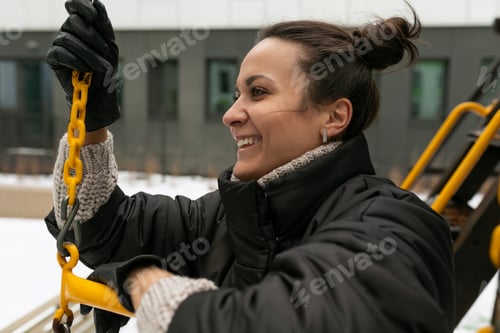 Preview: Young pretty woman in a winter jacket walking on the playground