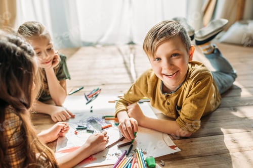 Preview: cute kids drawing on paper with pencils while lying on floor