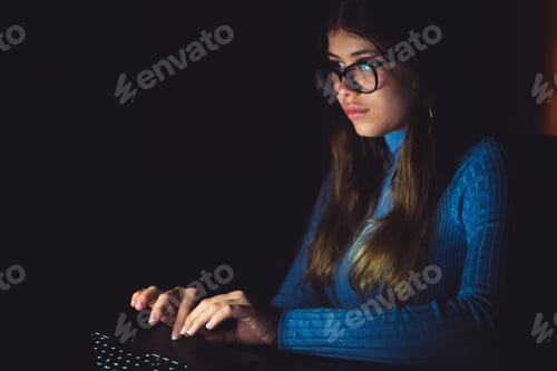 Preview: One beautiful and young woman using computer working at late night at home.
