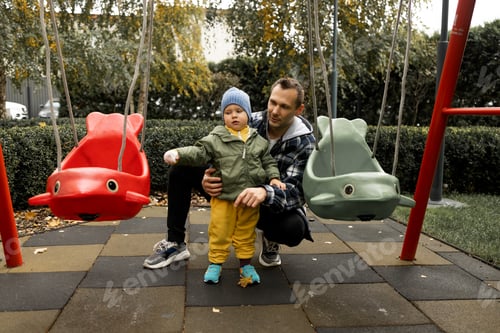 Preview: Young father playing with his little son on the playground in autumn park