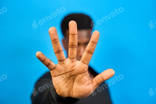 Preview: Businessman showing stop sign with hand on blue background