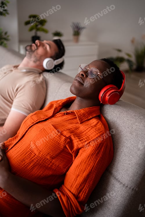 Preview: Couple relaxing on a sofa while listening to music in a cozy living room