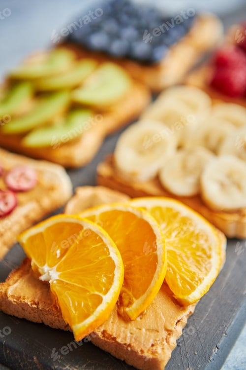 Preview: Six toasts with peanut butter, fresh fruits on a grey slate