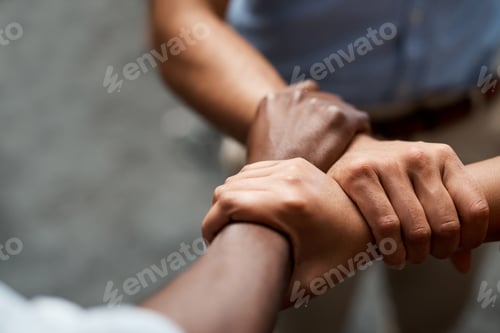 Preview: Shot of a group of businesspeople linking arms in solidarity in a modern office