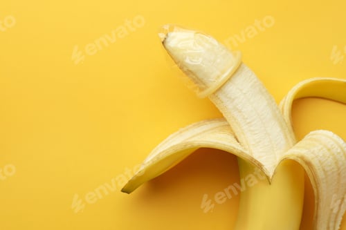 Preview: Banana with condom on orange background, top view and space for text. Safe sex concept