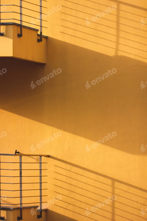Vorschau: Gelbe Wand mit Balkonen mit Schatten. Minimales Architekturkonzept.