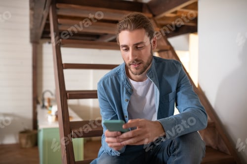 Preview: Man with Hair in Bun Uses Mobile Device