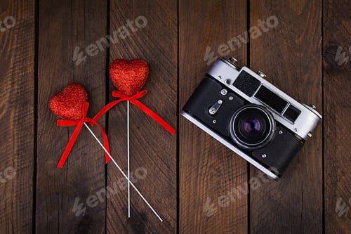 Preview: Vintage old camera with hearts on rustic wooden background. Top view