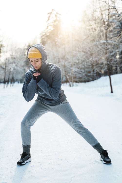 Preview: Young athletic woman warming up before her winter workout