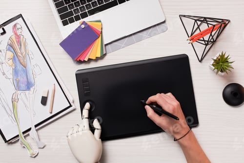 Preview: cropped female hands at designer office desk with robot hand using graphics tablet and pen