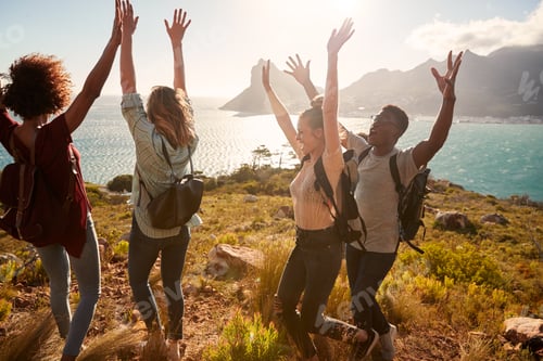 Preview: Millennial friends on a hiking trip celebrate reaching the summit, cheering with arms in the air