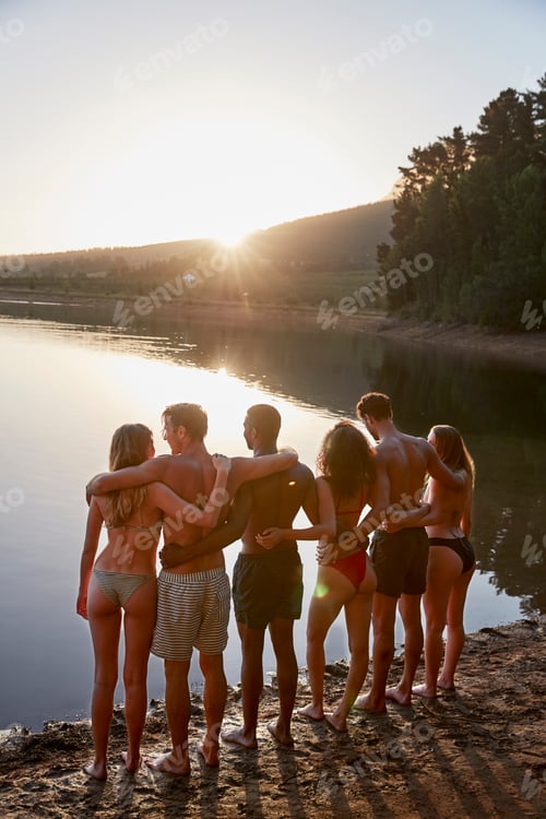 Preview: Young adult friends standing on lakeshore, vertical