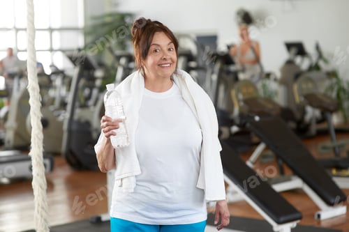 Preview: Senior woman holding bottle of water at gym