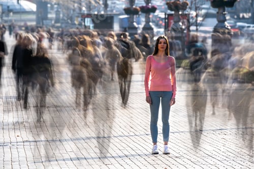 Preview: The young woman stands in the middle of crowded street.