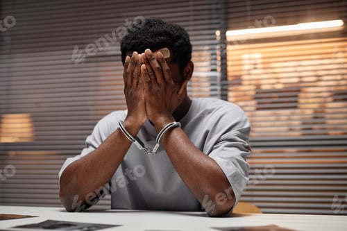 Preview: Black man wearing handcuffs as criminal covering face with hands crying