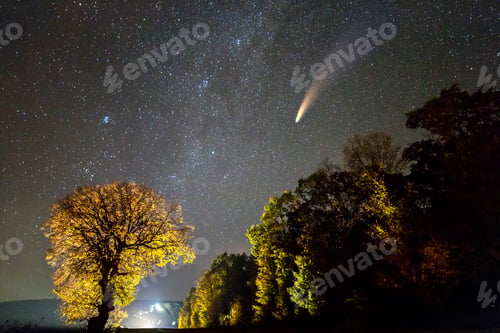 Preview: Night landscape with stars covered sky and comet with light tail.