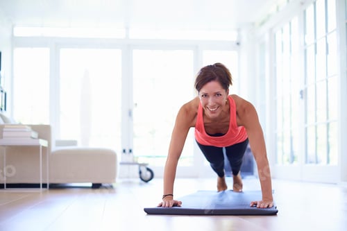 Preview: Mid adult woman doing press ups in living room