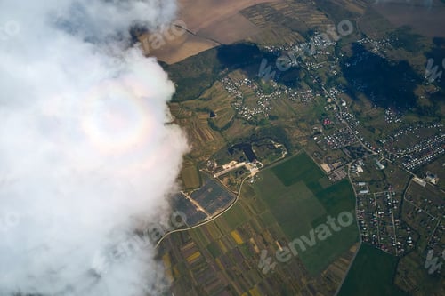 Preview: Aerial view from airplane window at high altitude of distant city covered with puffy cumulus clouds