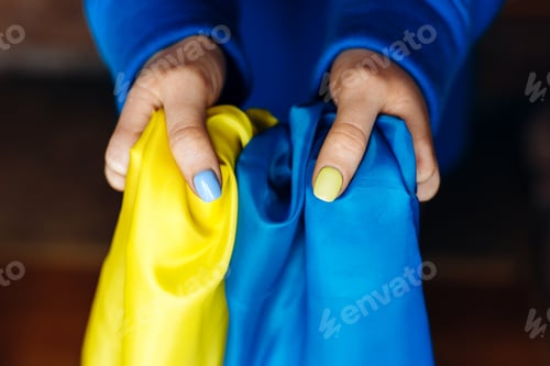 Preview: Woman with nails painted at the blue and yellow colours holding yellow-blue flag of Ukraine