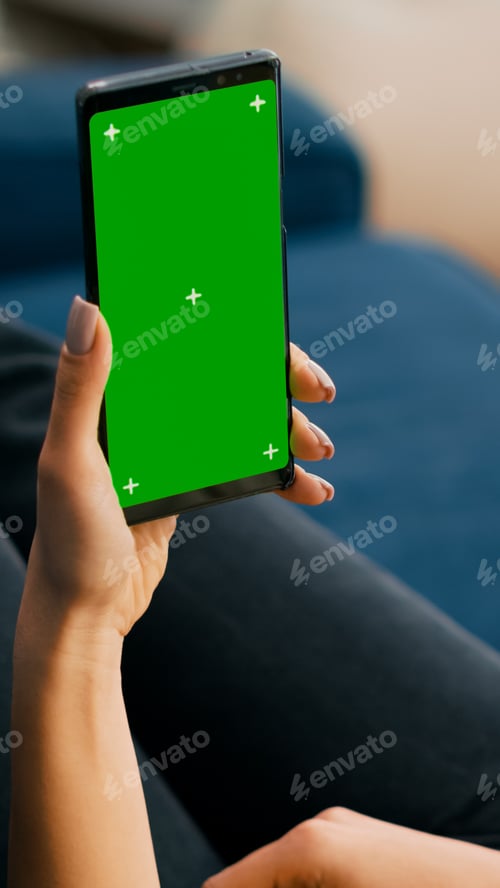 Preview: Freelancer holding in vertical mode smartphone with mock up green screen chroma key display