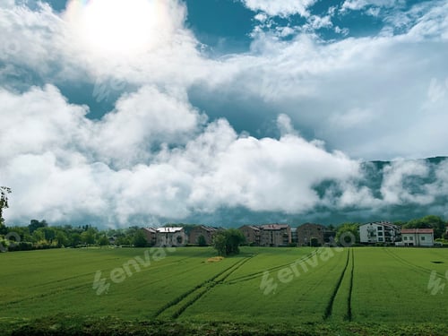 Preview: Beautiful sky. White puffy clouds over the mountain and green wheat field at sunny summer day