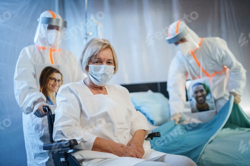Preview: Doctors and covid-19 infected patient in wheelchair in hospital, coronavirus concept.