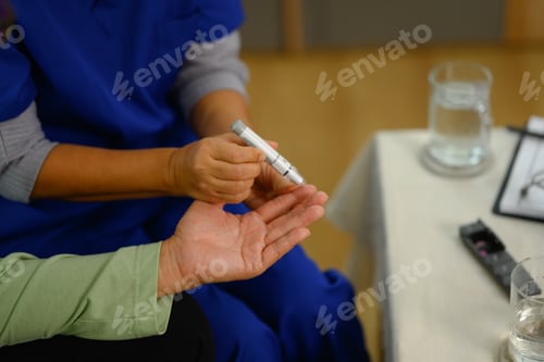 Preview: Medical worker using lancet on finger to checking blood sugar level senior patient at home