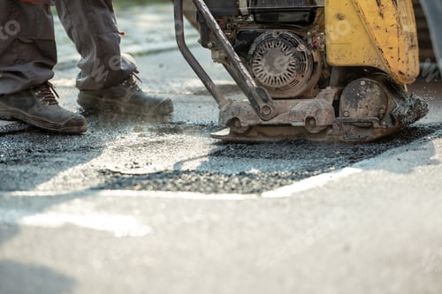 Preview: Worker using compactor to finish patching bump in the road