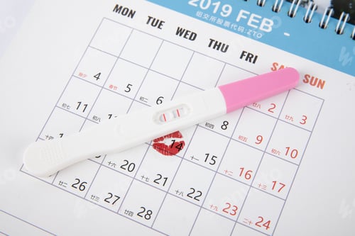 Preview: A pregnancy test kit with positive result on a calendar