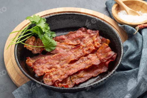 Preview: Crispy fried bacon in a cast iron pan.