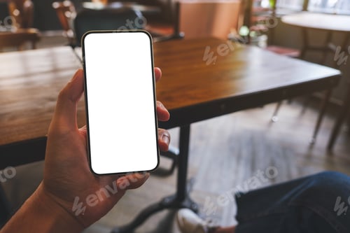 Preview: Mockup image of a man holding black mobile phone with blank white screen in cafe