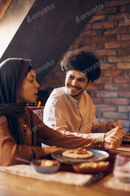 Preview: Young happy Muslim man enjoying in conversation with his wife during Ramadan Iftar meal.