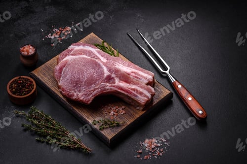 Preview: Fresh raw pork meat on the ribs with spices and herbs on a wooden cutting board