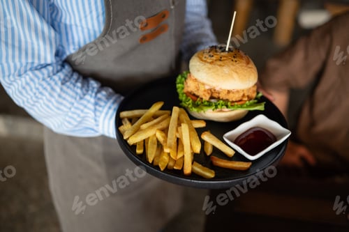 Preview: Waiter serves a fresh burger and fries in stylish restaurant, capturing the essence of great service
