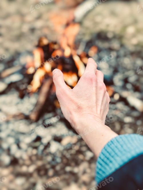 Hand Warming by Crackling Campfire on Beach