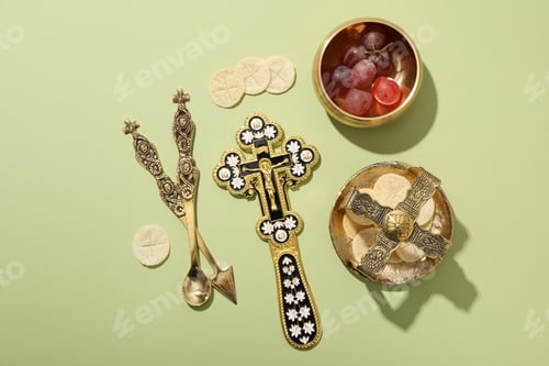 Preview: Liturgical bread, grapes in bowl and cross on green background, top view