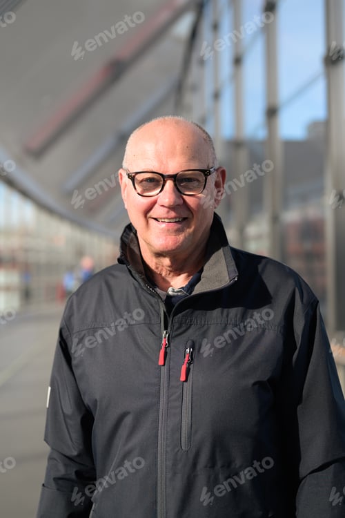 Preview: Portrait of a smiling senior man with eyeglasses at the railway station