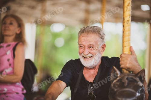 Preview: senior handsome elderly caucasian old man having fun with carousel in the park
