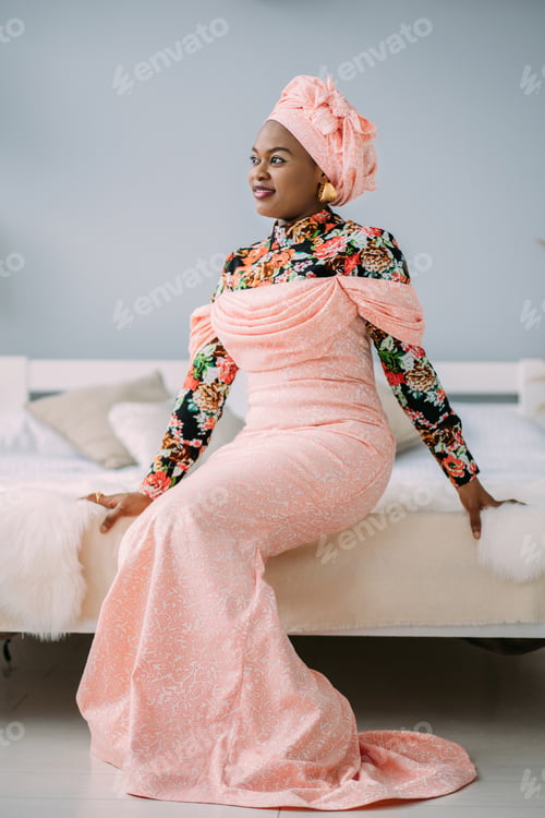 Preview: Young beautiful African lady wearing fashionable traditional pink dress and head scarf, earrings and