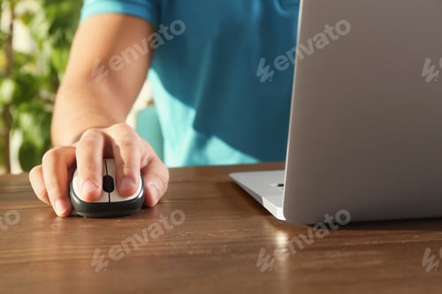 Preview: Man using computer mouse with laptop at table, closeup