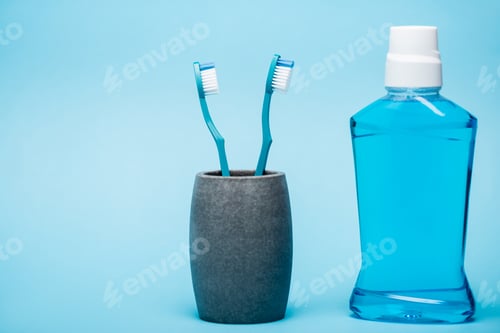 Preview: Toothbrushes and bottle of oral mouthwash on blue background