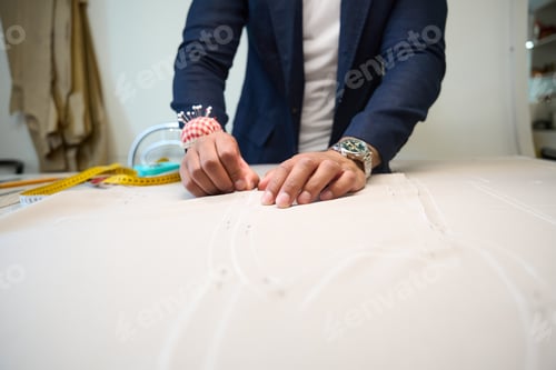 Preview: Tailor fastening cloth with pins before cutting on table