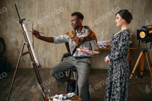 Preview: Woman watches as painter draws with a brush