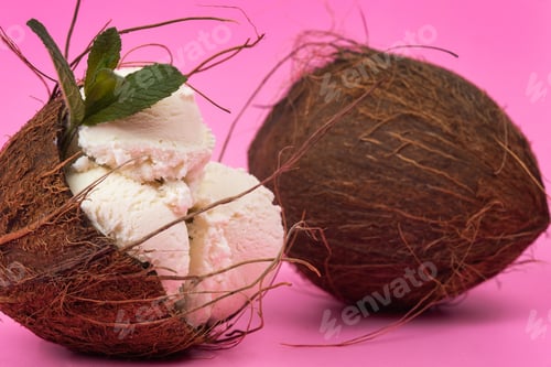 Preview: Vanilla ice cream balls in an empty coconut decorated with mint leaves on a pink background
