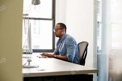 Preview: Office life. A man seated at a desk, using a computer screen.