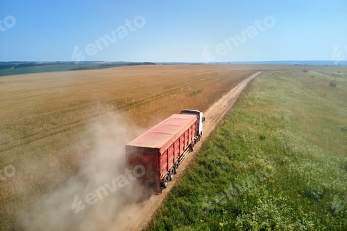 Preview: Aerial view of cargo truck driving on dirt road between agricultural wheat fields