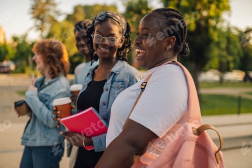 Preview: Side view of happy diverse female student walks at campus with classmates