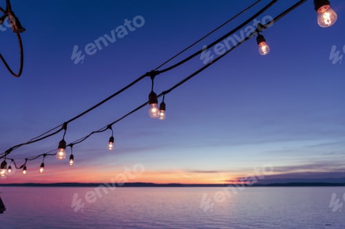 Preview: Hanging deck lights at sunset by the sea.