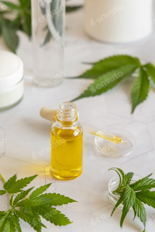 Preview: Opened Dropper bottle with pipette near green cannabis leaves. CBD oil