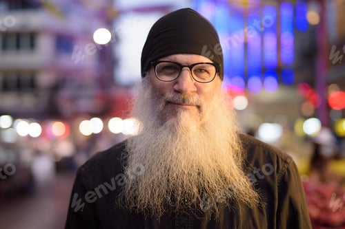Preview: Face of mature bearded tourist man with eyeglasses in Chinatown at night